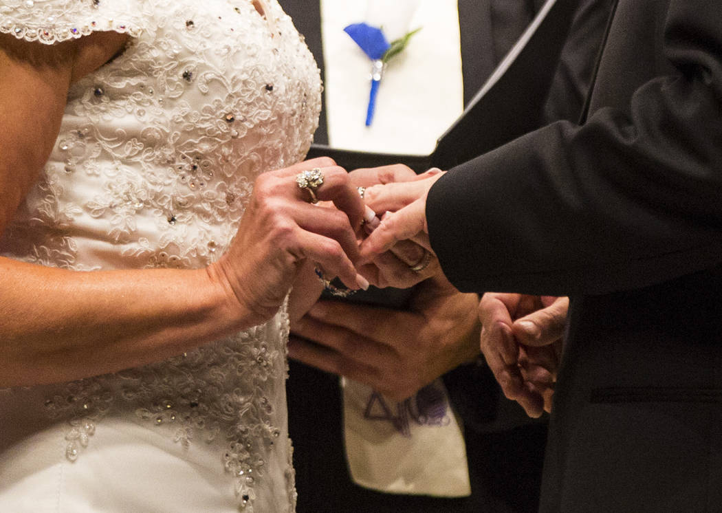 Oshia Collins-Waters, a la izquierda, pone un anillo en el dedo de Todd Wienke durante su ceremonia de boda en la Capilla de las Flores en Las Vegas el lunes 1 de octubre de 2018. Todd recibió tr ...