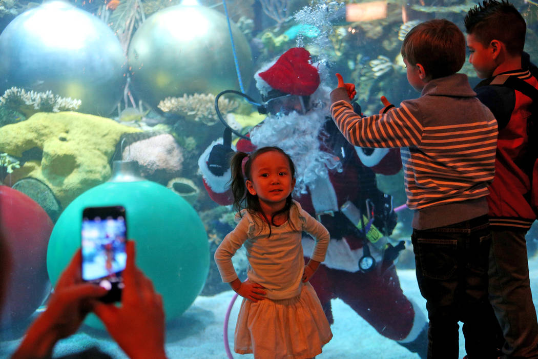 A Alyssa Kim, de 2 años, le tomaron una foto con Underwater Santa y saluda a la multitud en el hotel y casino Silverton en Las Vegas, el domingo 2 de diciembre de 2018. Él y la sirena navideña ...