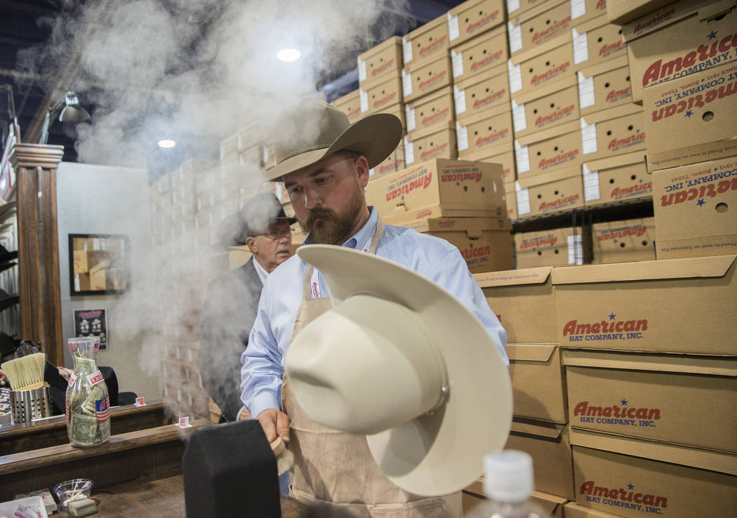 Tye Chesser, un representante de ventas de American Hat Company, ayuda a un cliente durante Cowboy Christmas en el Centro de Convenciones de Las Vegas el jueves 6 de diciembre de 2018, en Las Vega ...