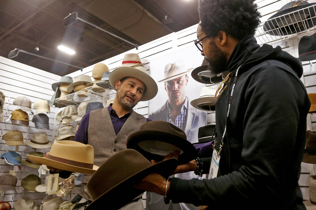 Victor Cornejo le muestra a Kevin Scott sombreros diferentes para comprar en el stand de Biltmore Hats en la feria de moda MAGIC en el Mandalay Bay Convention Center en Las Vegas, el miércoles 6 ...