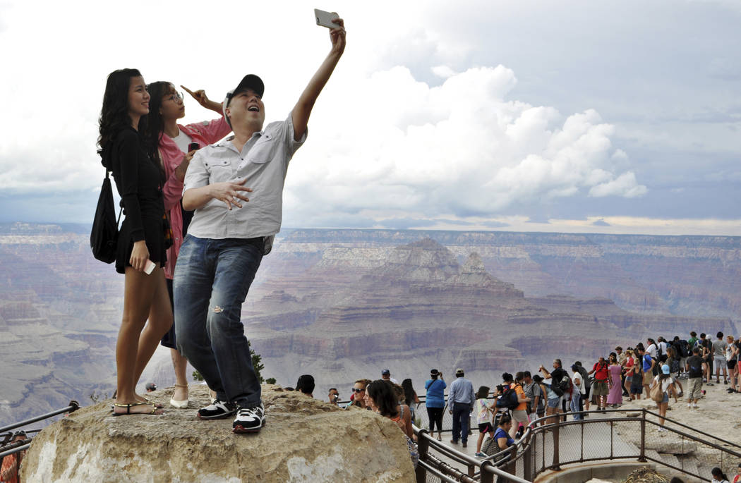 En esta foto de archivo del 2 de agosto de 2015, los turistas Joseph Lin, Ning Chao, centro, y Linda Wang, izquierda, posan para una selfie a lo largo del borde sur del Parque Nacional del Gran Ca ...