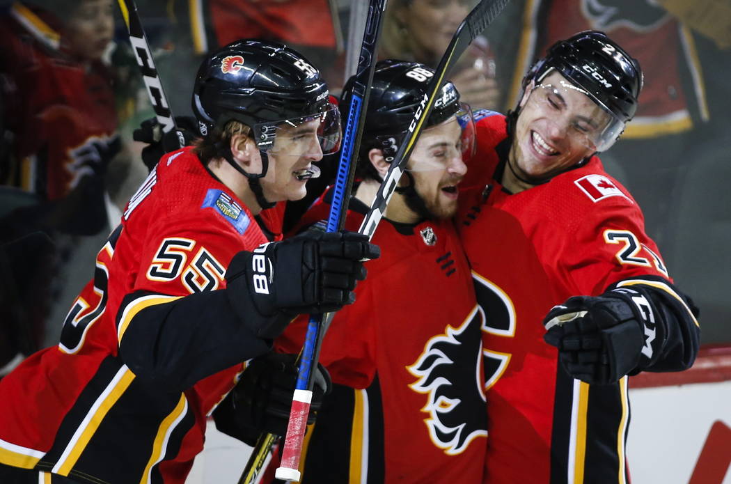 Andrew Mangiapane, centro de los Calgary Flames, celebra su gol con sus compañeros Noah Hanifin, a la izquierda, y Garnet Hathaway durante el primer período de acción de hockey de la NHL contra ...