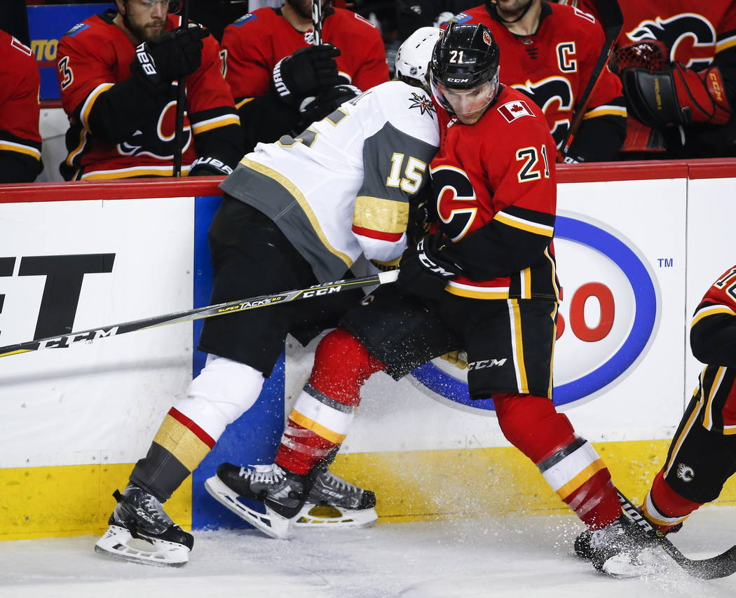 Jon Merrill de los Vegas Golden Knights, a la izquierda, controla a Garnet Hathaway de los Calgary Flames durante el tercer período de un juego de hockey de la NHL en Calgary, Alberta, el domingo ...