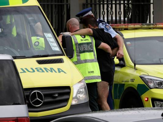 La policía y el personal de ambulancias ayudan a un hombre herido desde afuera de una mezquita en el centro de Christchurch, Nueva Zelanda, el viernes 15 de marzo de 2019. (AP Photo / Mark Baker)