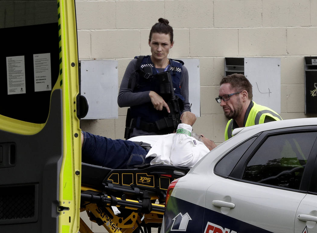 Un oficial de policía armado observa a un personal de ambulancia que asiste a un hombre de una mezquita en el centro de Christchurch, Nueva Zelanda, el viernes 15 de marzo de 2019. (AP Photo / Ma ...