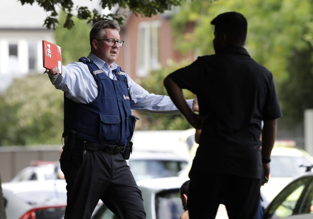 Un oficial de policía intenta alejar a las personas del otro lado de la carretera de una mezquita en el centro de Christchurch, Nueva Zelanda, el viernes 15 de marzo de 2019. (AP Photo / Mark Baker)