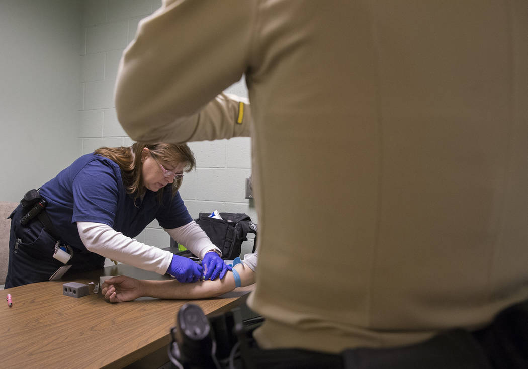 La Dra. Katharine York, a la izquierda, extrae sangre de un supuesto conductor incapacitado en la Oficina de Tránsito del Metro como parte de una "campaña de DUI" el jueves 14 de marzo de 2019, ...
