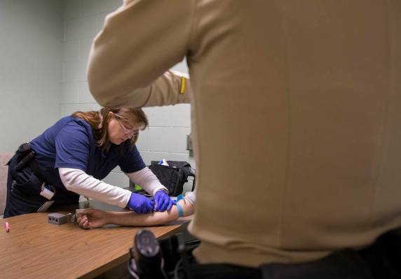 La Dra. Katharine York, a la izquierda, extrae sangre de un supuesto conductor incapacitado en la Oficina de Tránsito del Metro como parte de una "campaña de DUI" el jueves 14 de marzo de 2019, ...