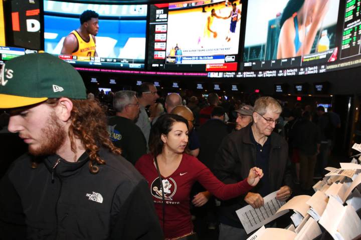 Fans, incluyendo a Ivette Abramyan, al centro, de Jacksonville, Florida, se alinearon para hacer sus apuestas durante el primer día del torneo de baloncesto de la NCAA en la casa de apuestas de W ...