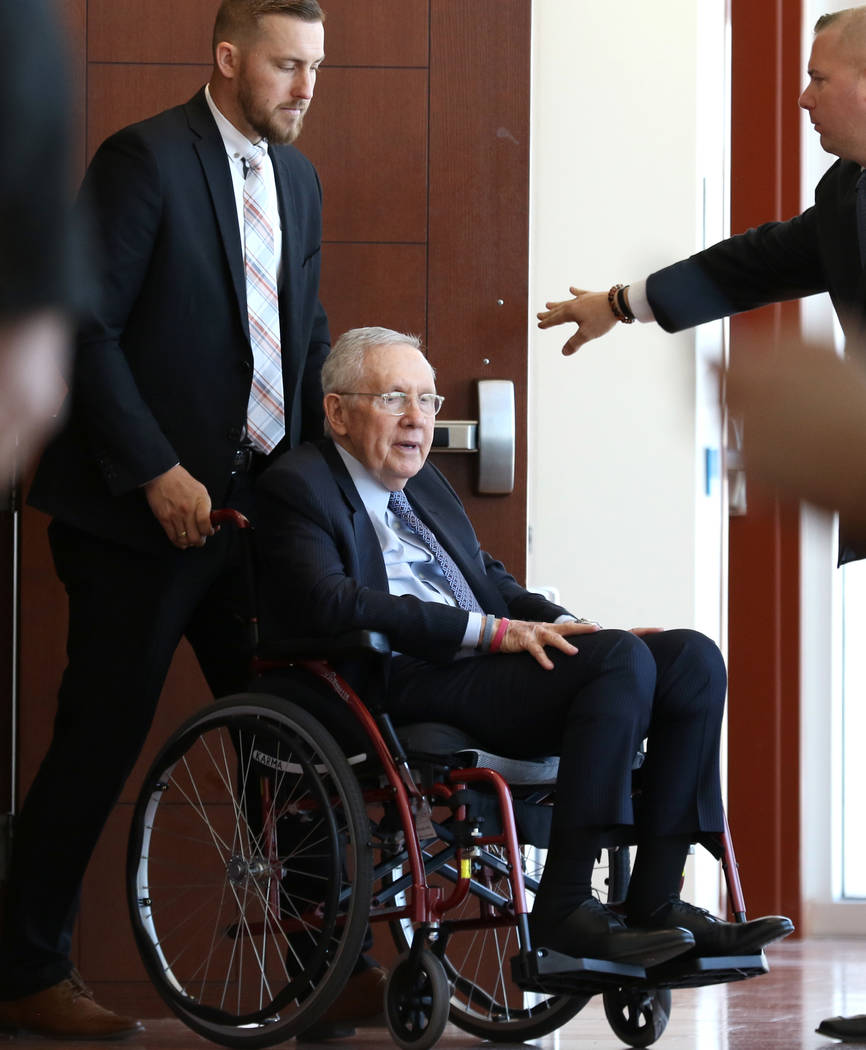 El ex senador estadounidense Harry Reid, quien demandó a los creadores de una banda de ejercicio después de lesionarse el ojo, abandona la sala de audiencias en una silla de ruedas después de a ...