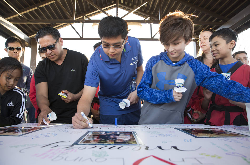 Los asistentes firman un cartel en honor a la memoria de Jonathan Smith, de 12 años, durante u ...