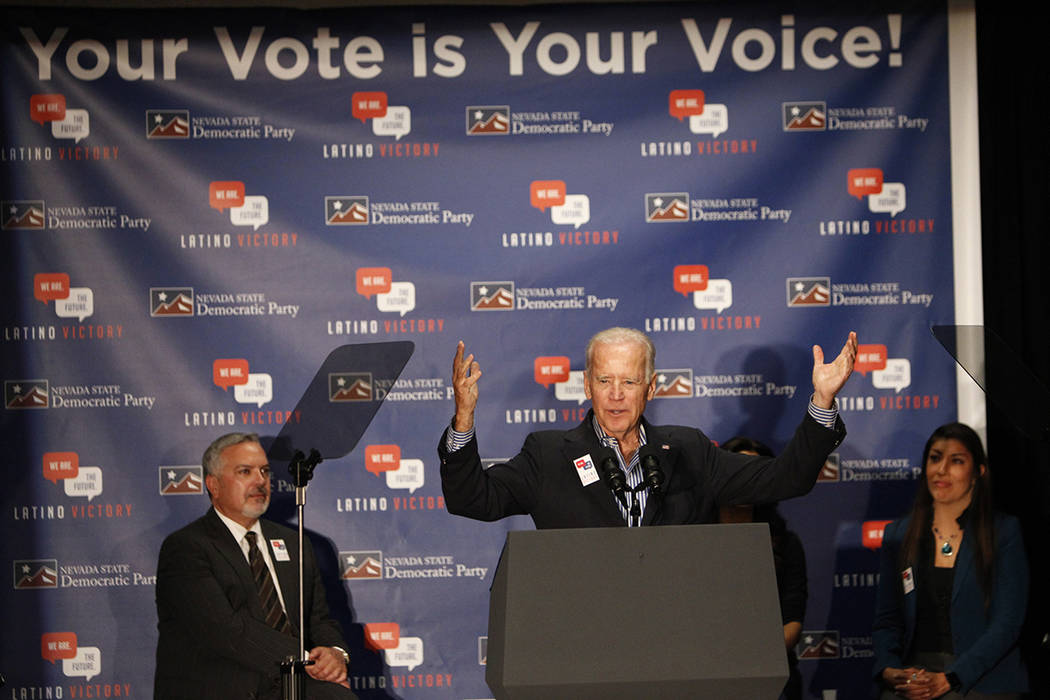 El vicepresidente Joe Biden, en el centro, habla durante un evento de votación, con Henry R. M ...