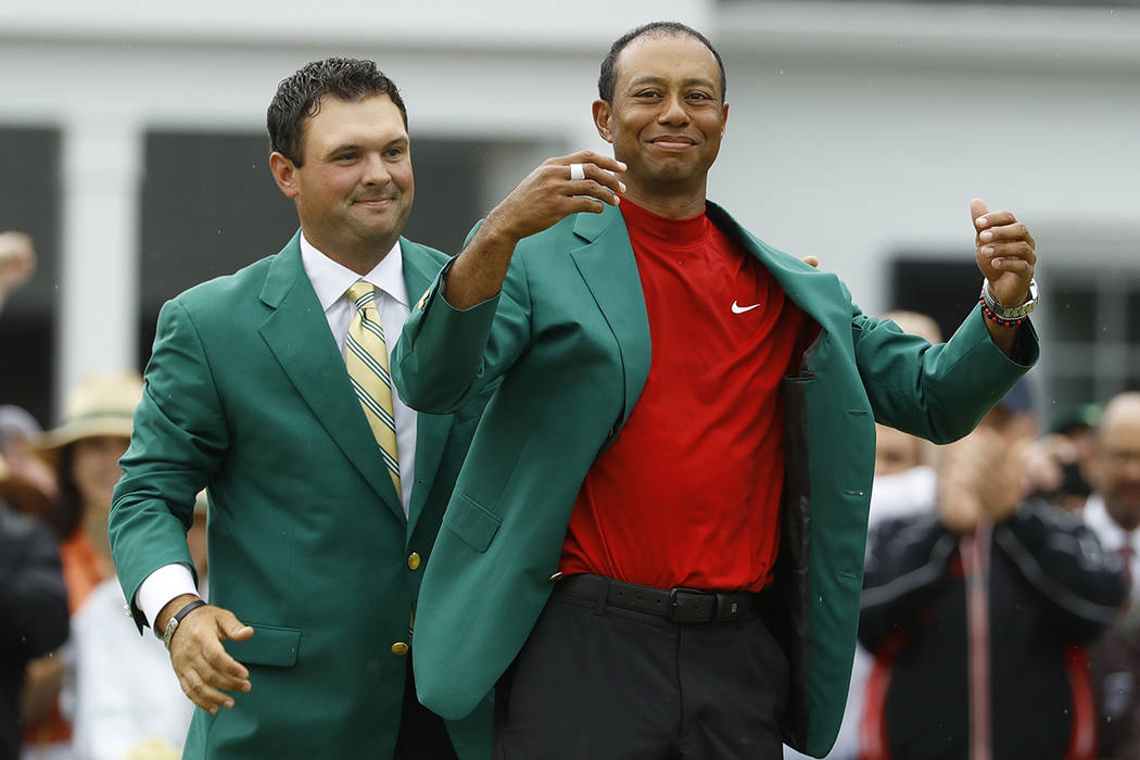 Patrick Reed ayuda a Tiger Woods con su chaqueta verde después de que Woods ganó el torneo de ...