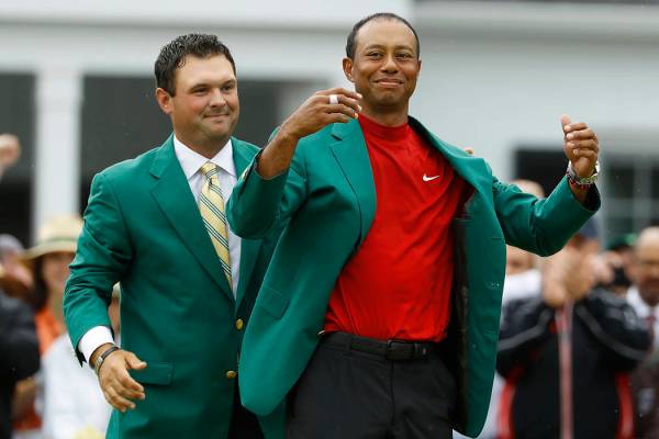 Patrick Reed ayuda a Tiger Woods con su chaqueta verde después de que Woods ganó el torneo de ...