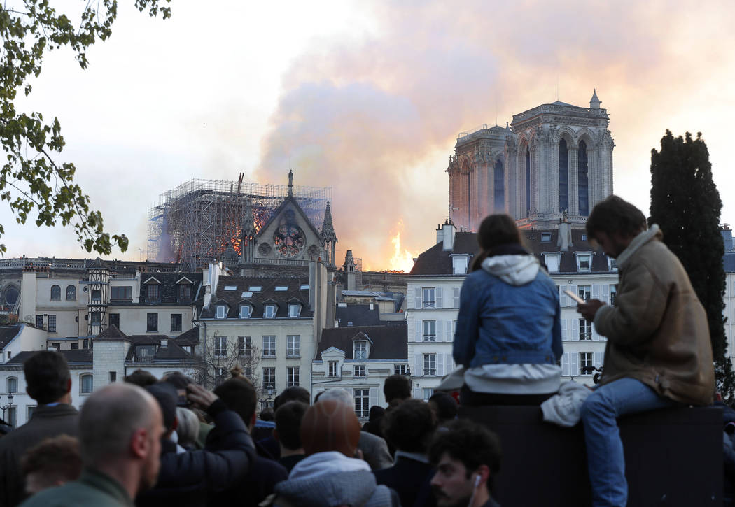 La gente ve cómo las llamas y el humo se elevan desde la catedral de Notre Dame mientras se qu ...