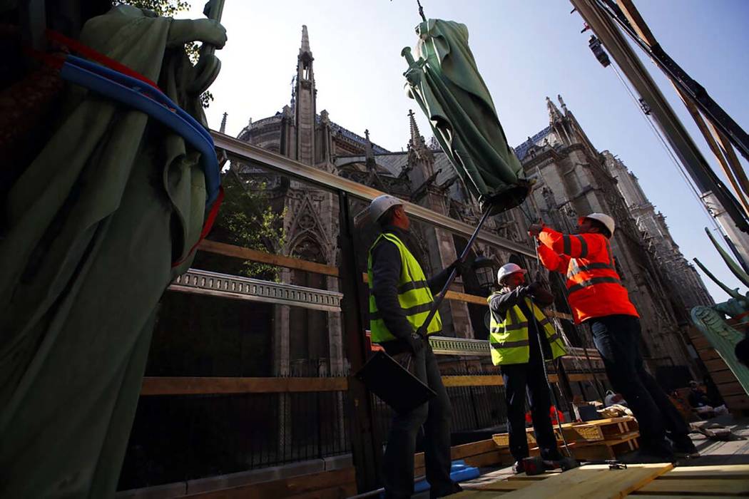 Los trabajadores aseguran una estatua religiosa posada en lo alto de la Catedral de Notre Dame ...