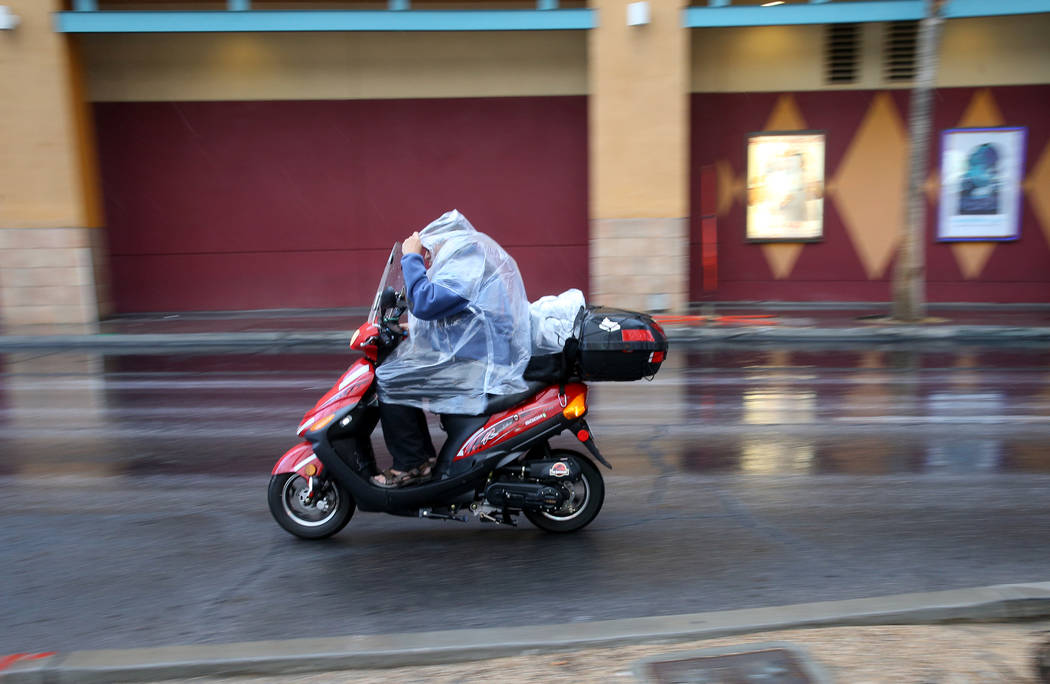 Un conductor de scooter se protege de una lluvia ligera en Las Vegas Boulevard, cerca de Fremon ...