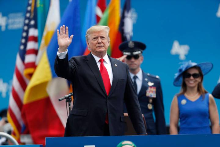 El presidente Donald Trump saluda mientras sube al escenario para hablar en la graduación de l ...