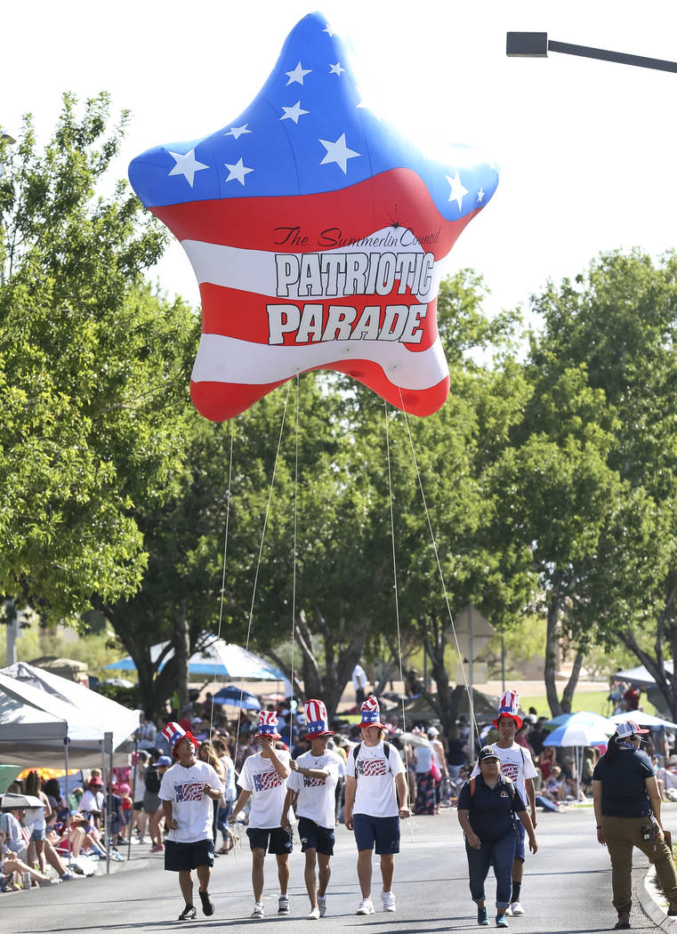 Los participantes caminan con un globo de estrella patriótica para comenzar el desfile del Con ...