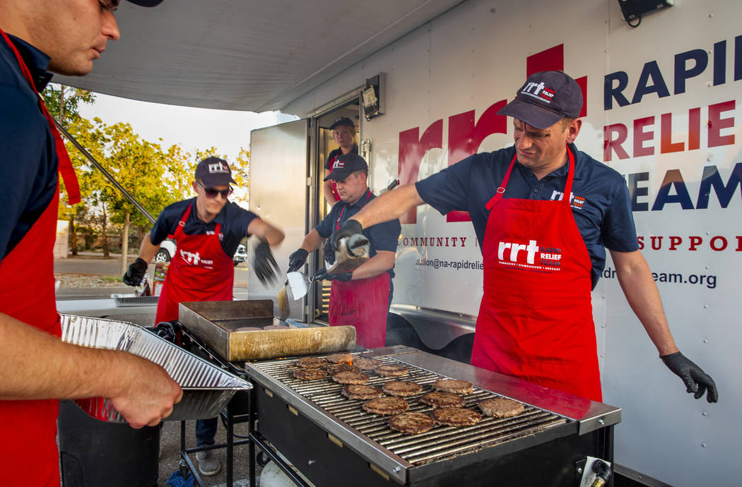 Los miembros de un Equipo de Ayuda Rápida de la Cruz Roja se preparan para servir hamburguesas ...