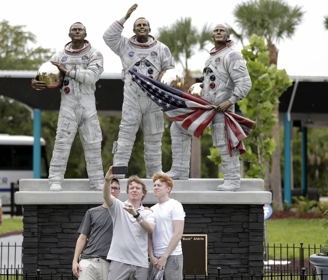 Los invitados se toman una foto frente a una nueva estatua de los astronautas del Apolo 11, de ...