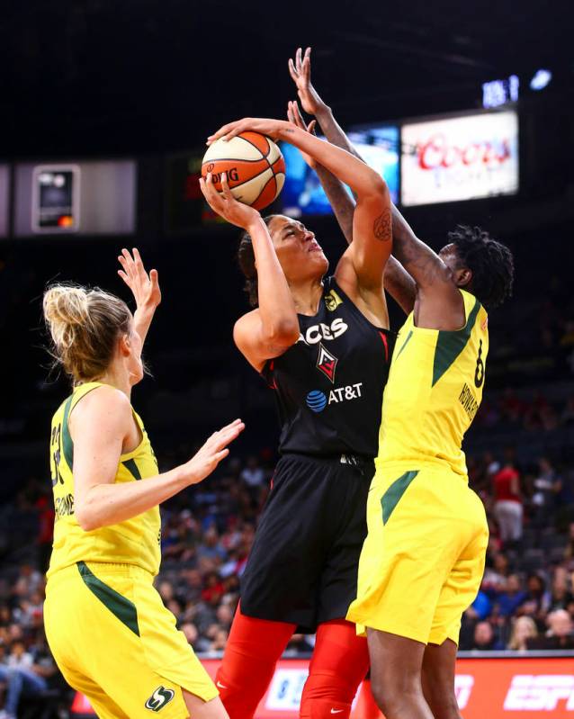 Liz Cambage, centro de Las Vegas Aces, va hacia la canasta entre Sami Whitcomb, izquierda de Se ...