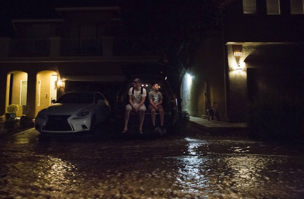 Jonathan Smedley, a la izquierda, y su hijo Cameron observan las aguas de las inundaciones pasa ...