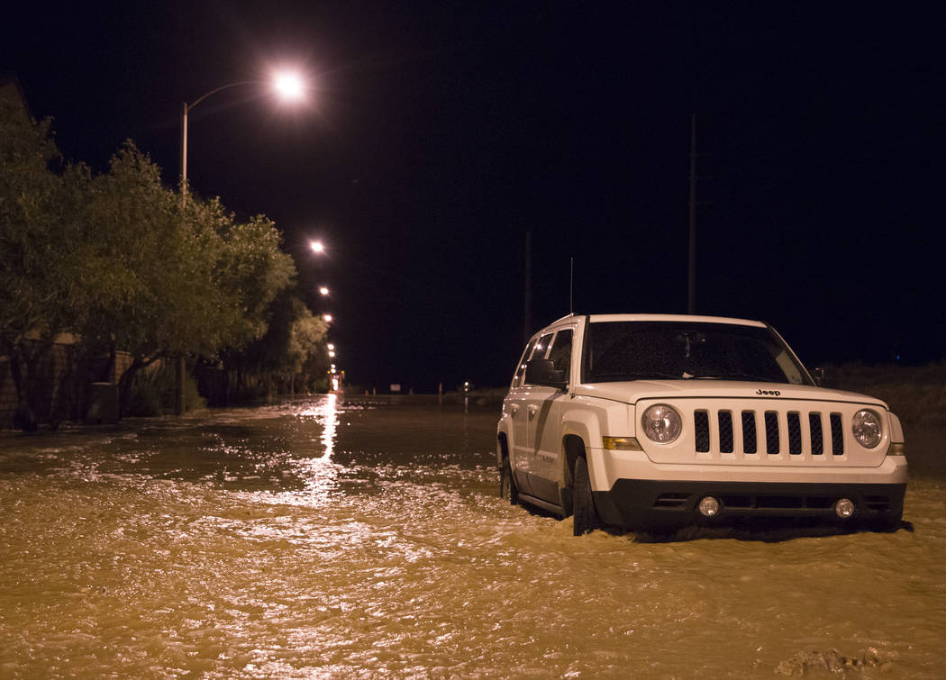 Un vehículo está atrapado en las aguas de la inundación en la intersección de West Fitzwill ...