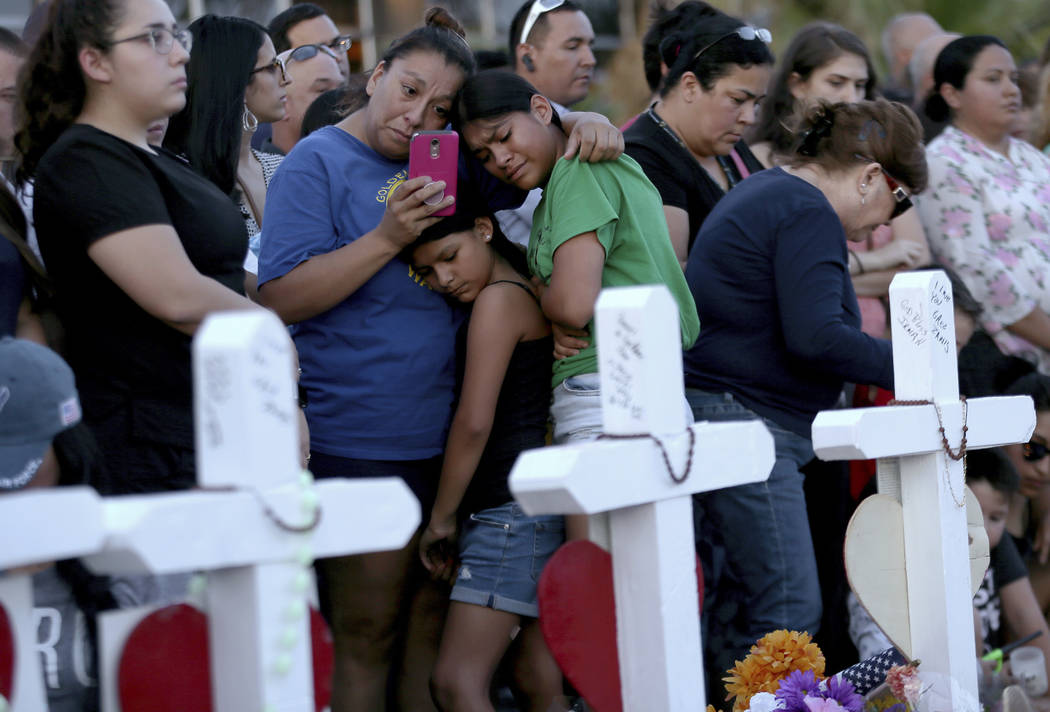 Una madre se aferra a sus hijas mientras visitan un monumento conmemorativo para las víctimas ...