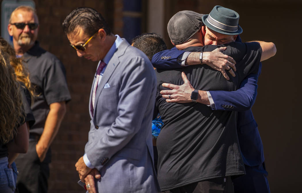 Jason Deborski, de espaldas, recibe un abrazo mientras dolientes se reúnen para el funeral de ...