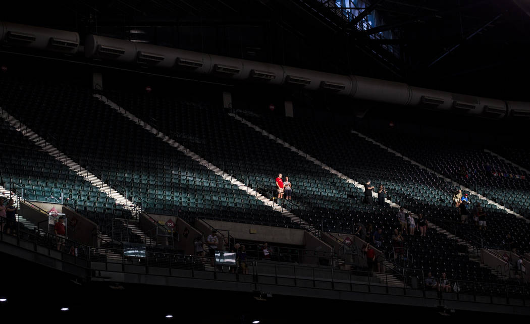 Fans resaltados por una franja de luz solar antes del comienzo de un juego de béisbol de los D ...