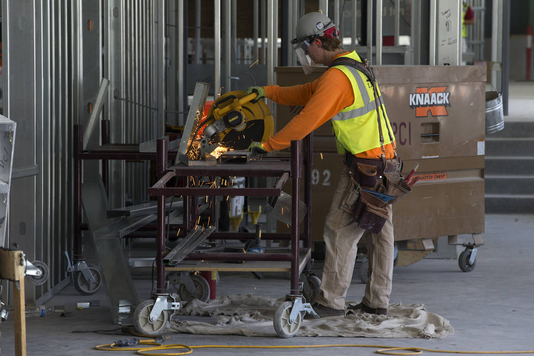 Un trabajador corta una pieza de metal en el sitio de construcción del estadio Raiders Allegia ...