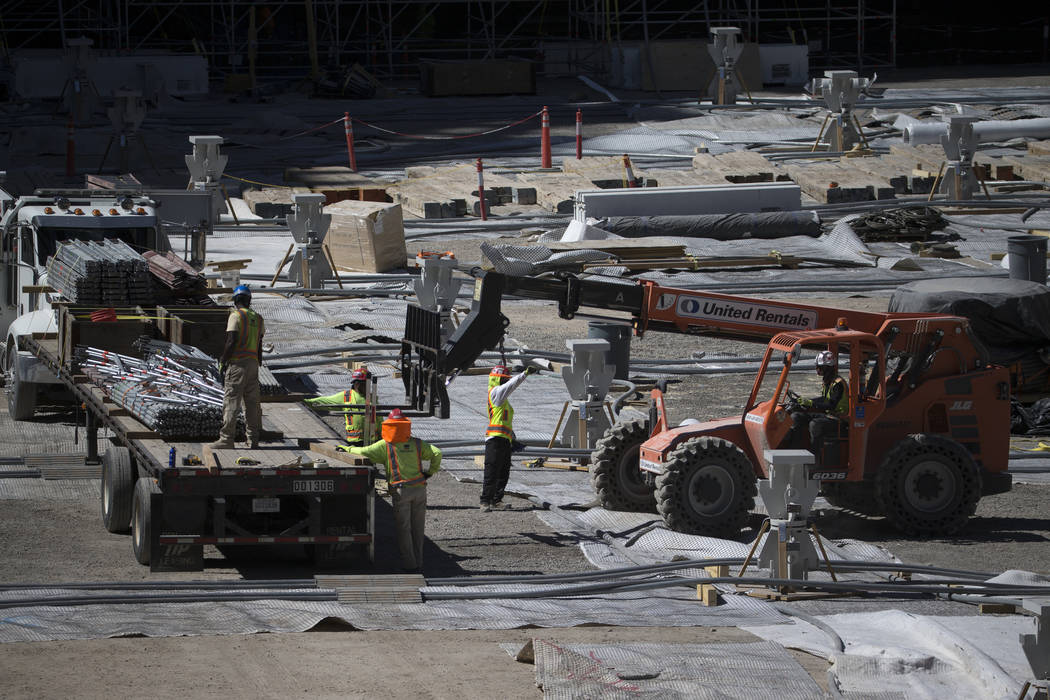 Los trabajadores mueven el equipo desde el nivel del piso del sitio de construcción del estadi ...