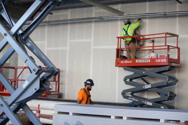 Un trabajador, a la derecha, parcha una pared en el sitio de construcción del estadio Raiders ...