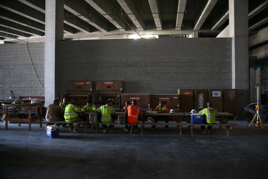 Trabajadores se sientan para almorzar en el sitio de construcción del estadio Raiders Allegian ...