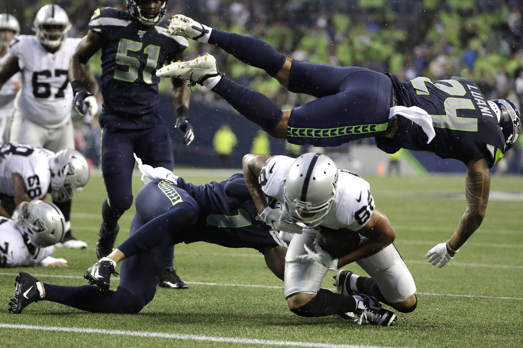 El defensa de los Seahawks de Seattle, Shalom Luani (24), vuela sobre el receptor abierto de lo ...