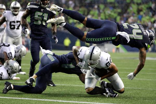 El defensa de los Seahawks de Seattle, Shalom Luani (24), vuela sobre el receptor abierto de lo ...