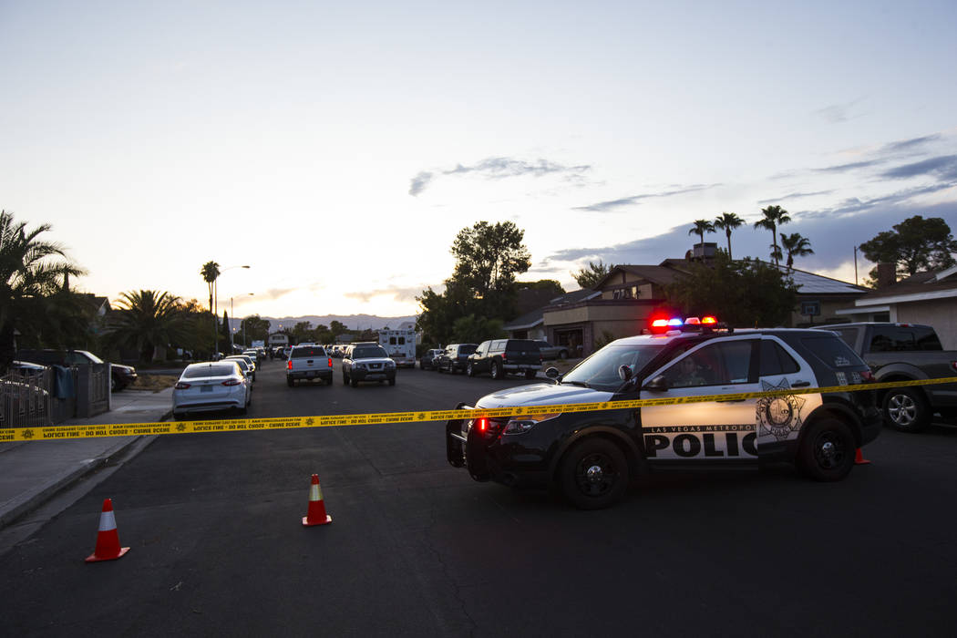 La policía de Las Vegas asegura el área alrededor de una calle residencial mientras esperan u ...