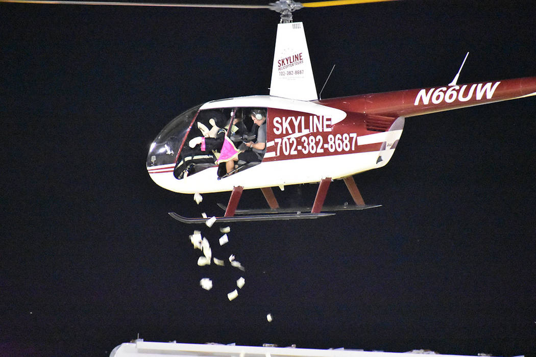 La mascota “Cash” arrojó dinero desde un helicóptero para 200 aficionados durante el medi ...