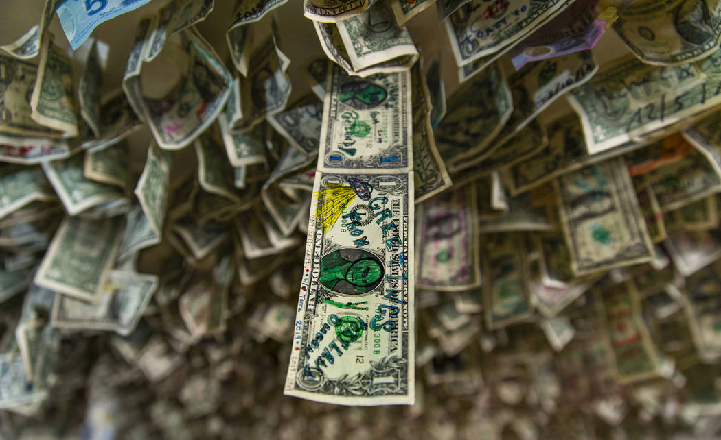 Un billete de un dólar con un dibujo extraterrestre cuelga con muchos otros billetes sobre el ...