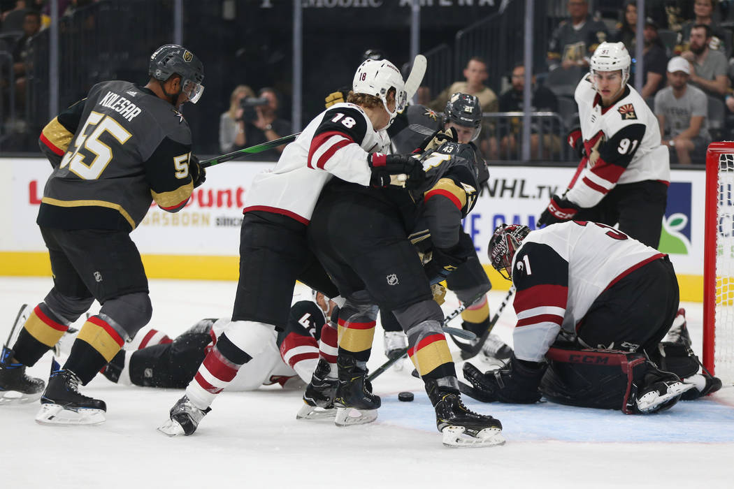 Jugadores luchan por el puck durante el primer tiempo de un juego de hockey de pretemporada de ...