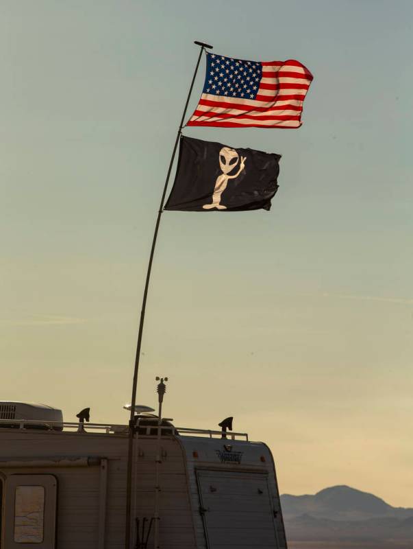 Dos banderas ondean y una casa rodante está estacionada en el desierto mientras se acercan los ...