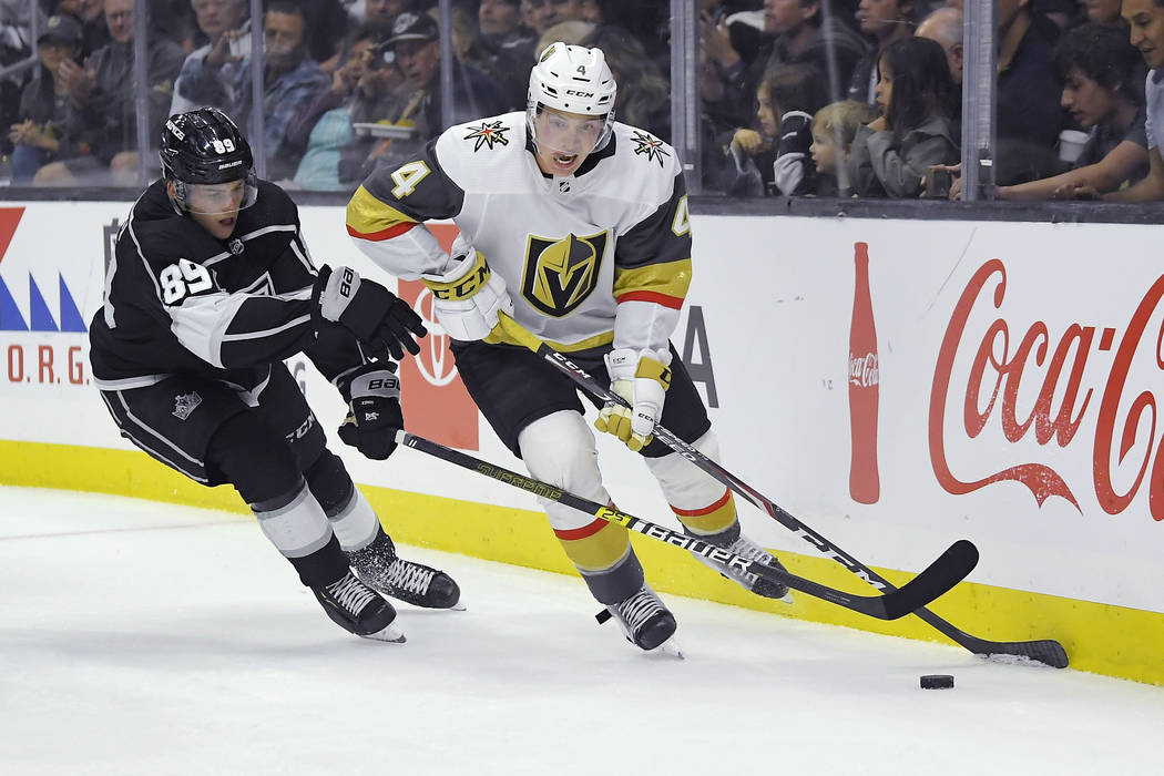 El defensor de los Golden Knights de las Vegas, Jimmy Schuldt, a la derecha, mueve el puck bajo ...