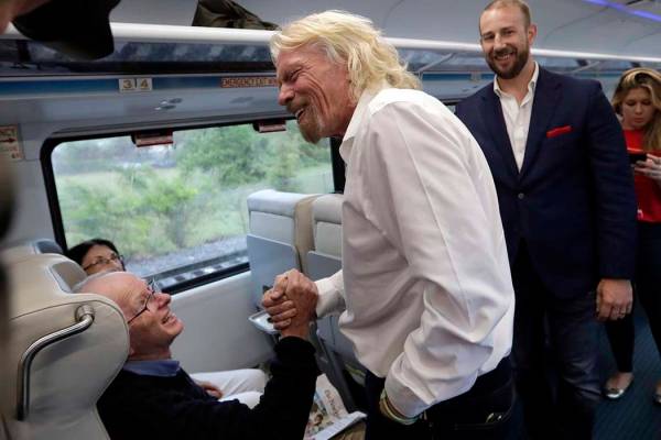 Richard Branson, del Virgin Group (al centro), saluda a un pasajero mientras viaja en un tren B ...