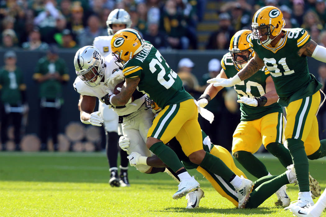 El esquinero de los Green Bay Packers, Jaire Alexander (23), derriba al corredor de los Oakland ...