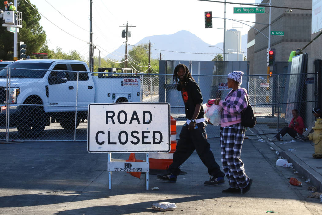 Clientes caminan al lado de un letrero de carretera cerrada afuera del Courtyard Homeless Resou ...