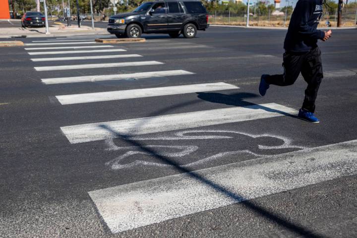 Un peatón cruza contornos de tiza recién pintados por el Departamento de Bomberos de Las Vega ...