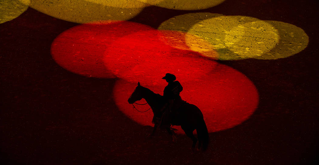 El hombre de seguridad Derrick Begay bañado en luces de colores durante la apertura de las Fin ...