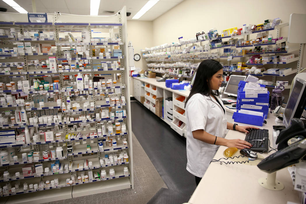 La gerente de farmacia, María Masood, atiende la receta de un cliente en la farmacia Walgreens ...
