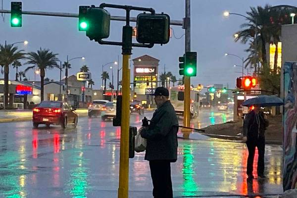 Peatones cruzan el Strip de Las Vegas cerca del Caesars Palace bajo la lluvia el miércoles, 20 ...